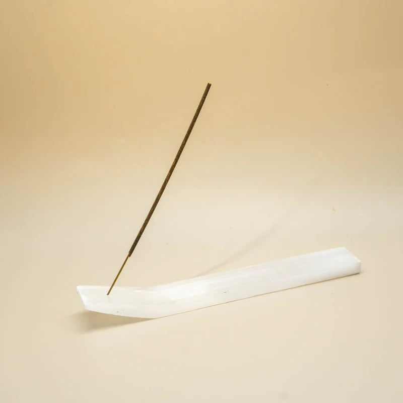 Incense stick on a white dish against a beige background